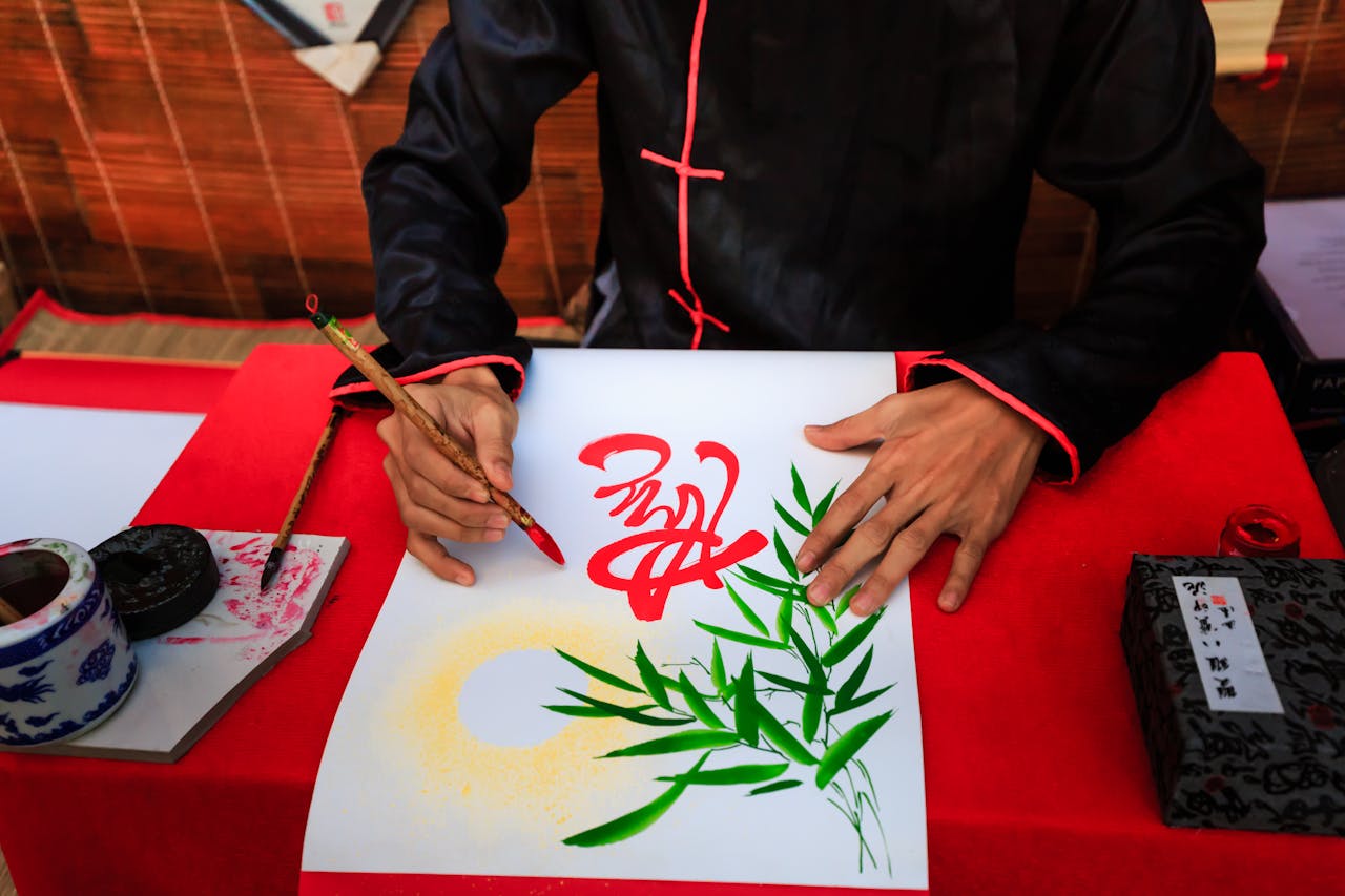 Artist crafting Asian calligraphy with vivid colors and bamboo design.