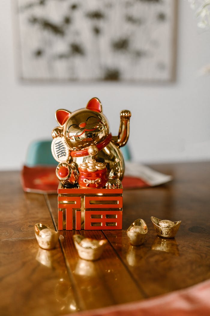 Golden lucky cat figurine with gold ingots reflecting prosperity and tradition on a wooden surface.